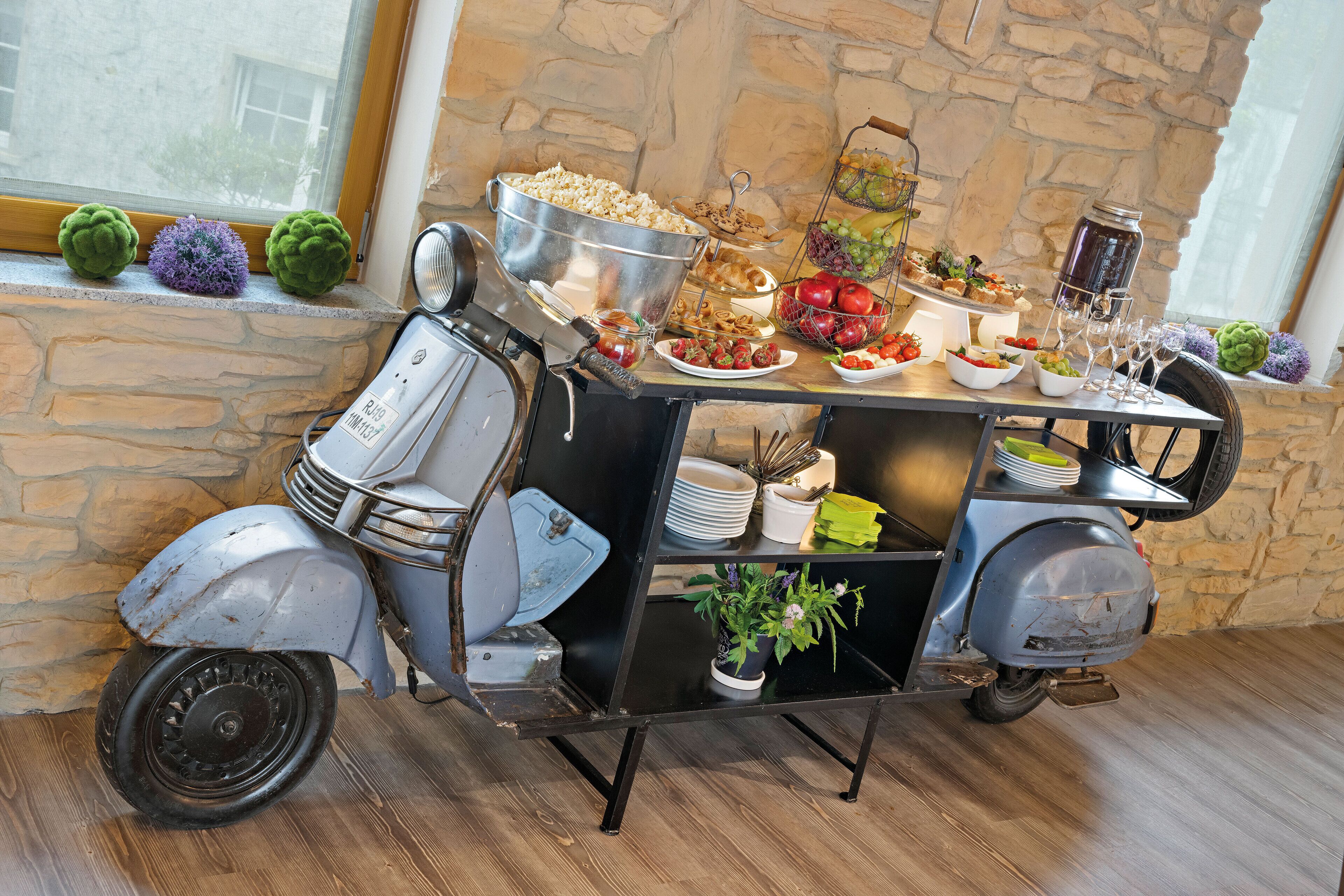 En vintage scooter brugt som buffetbord med forskellige retter og drikkevarer.