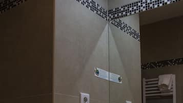 Ein Badezimmer mit Waschbecken, Spiegel, Handtuchhalter und Fliesen.