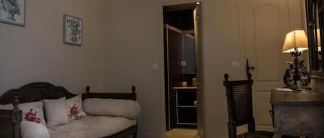 Une pièce comprenant un canapé en bois, une chaise, une table avec une lampe et une porte donnant sur un placard.