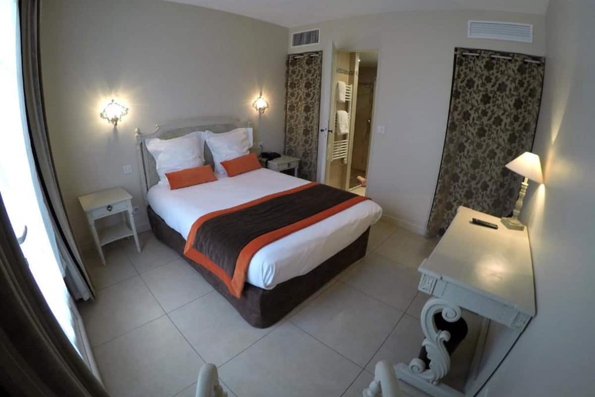 Une chambre d’hôtel avec un lit, des tables de chevet, un bureau et une chaise.