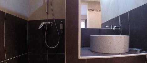 Une salle de bain avec une douche, un lavabo et une serviette sur le sol.