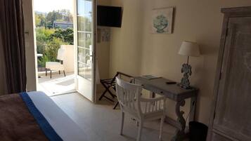 A hotel room with a bed, a desk, a chair, a TV, and a view of the outdoors.