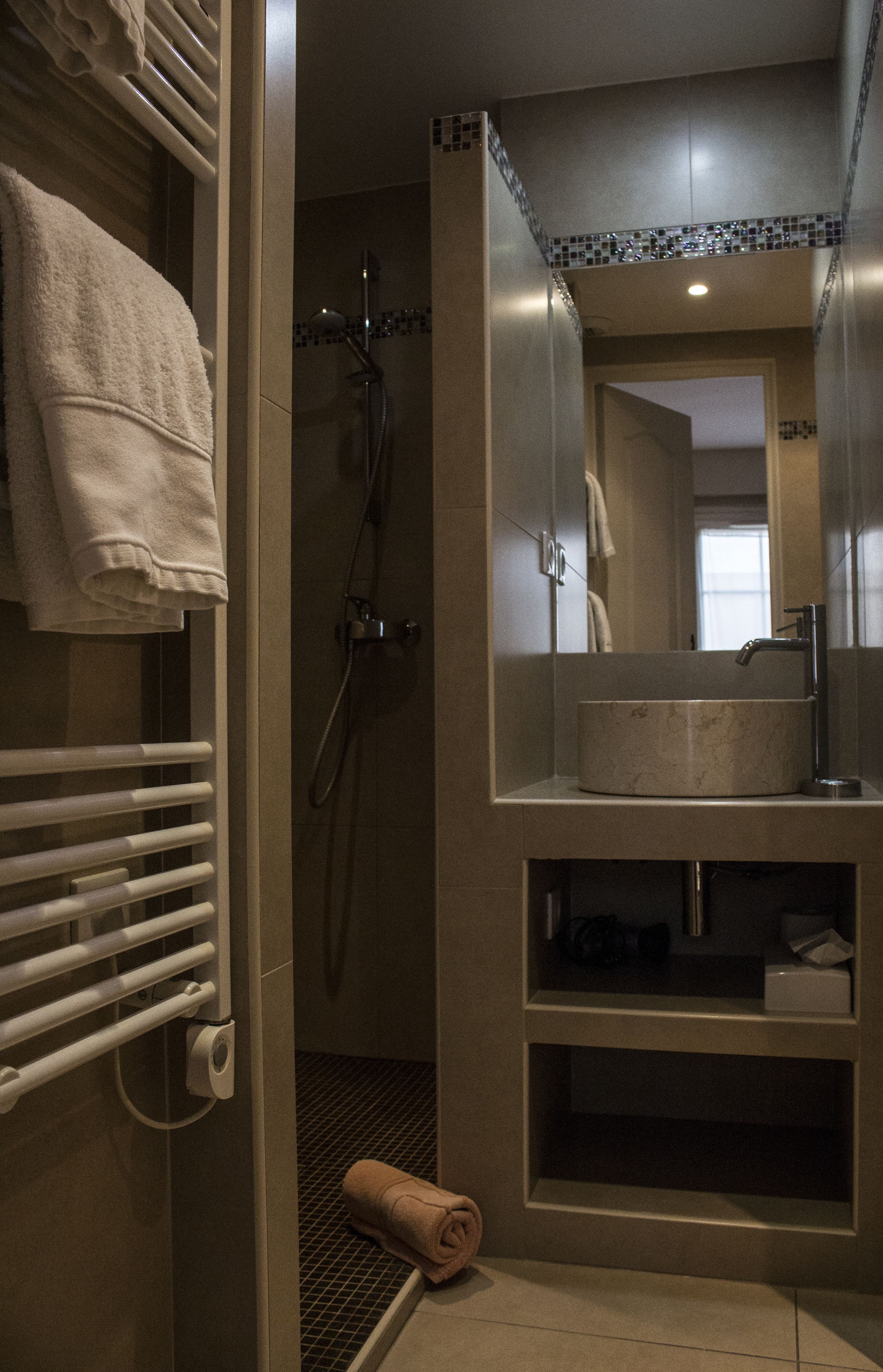 Ein Badezimmer mit Dusche, Waschbecken, Handtuchhalter und Spiegel.