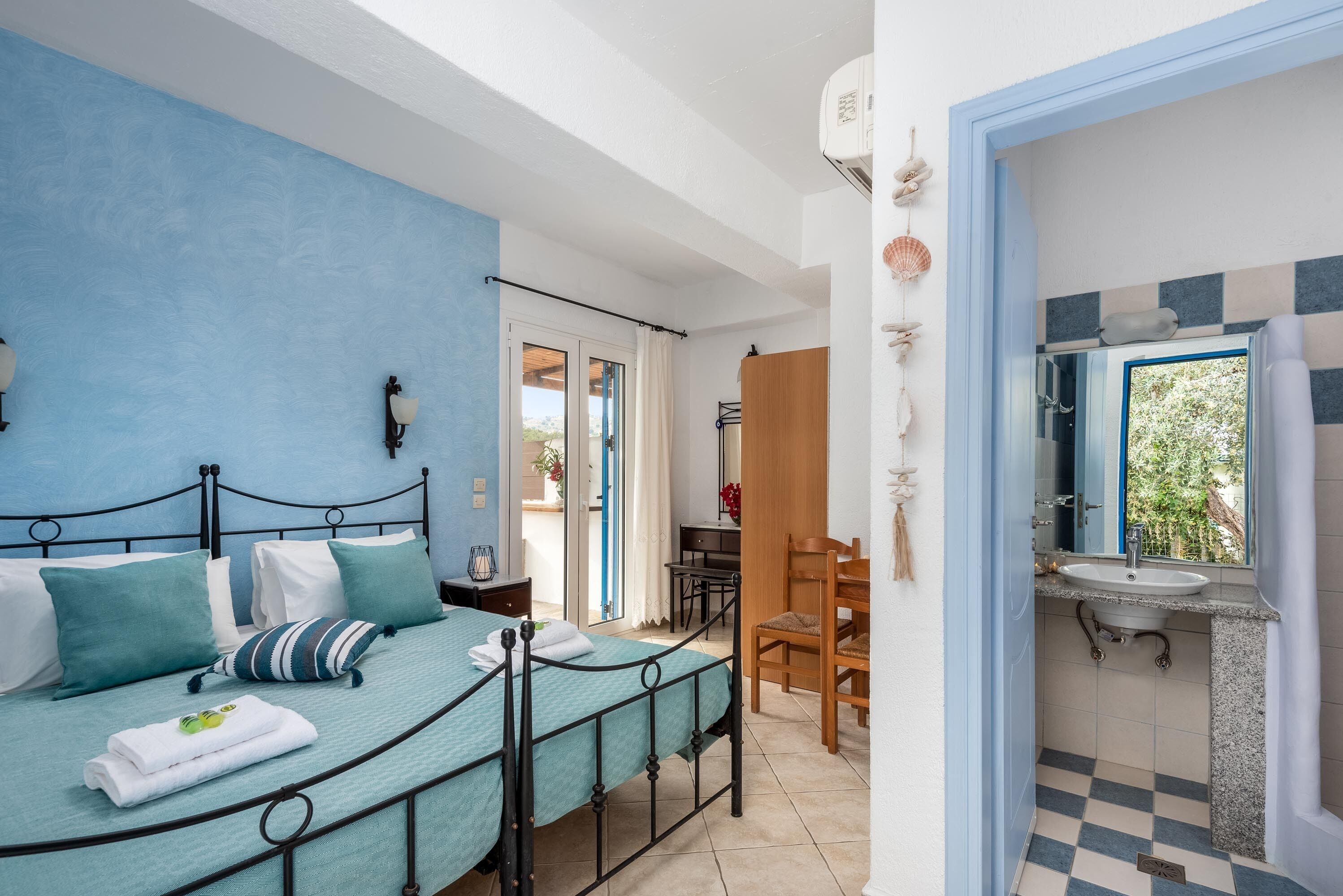 Une chambre à coucher comprenant un lit, un bureau et une salle de bain avec un lavabo et un miroir.