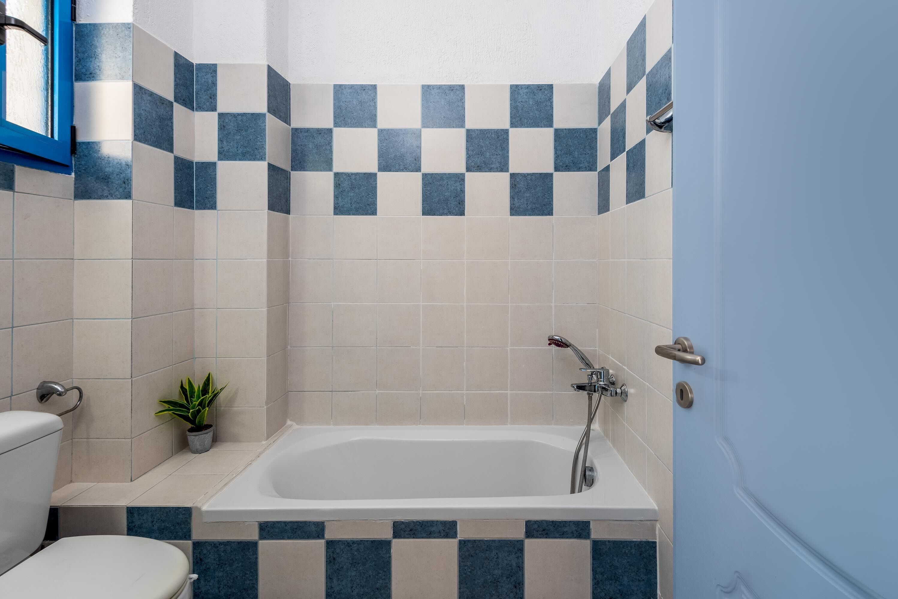 Een badkamer met een bad, toilet en een kleine plant in een pot.