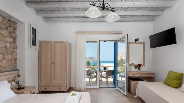 Habitación de hotel con cama, escritorio, armario, televisor y vista al mar.