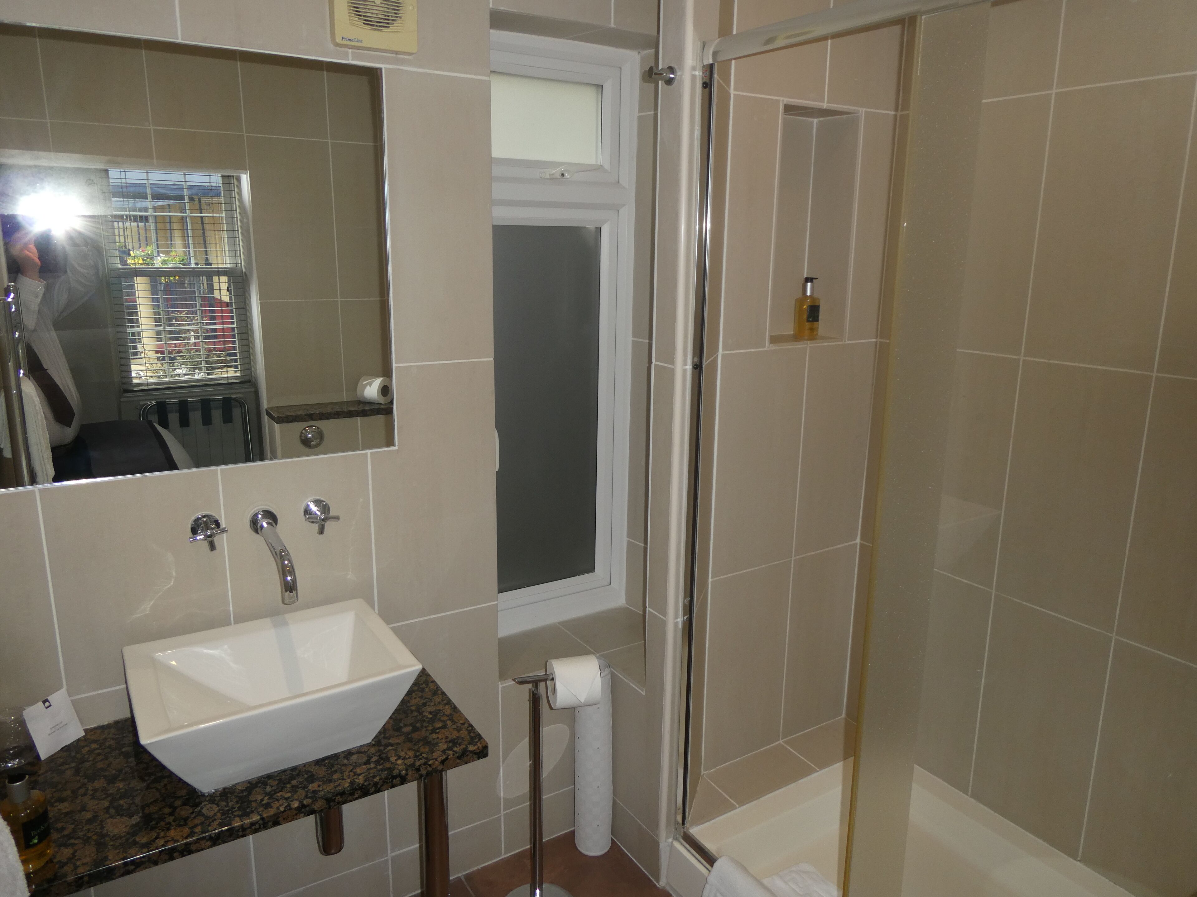 A bathroom with a sink, mirror, shower, and toilet.