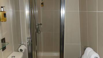 A bathroom with a shower, toilet, sink, and towel rack.