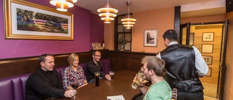 A group of people seated around a table in a restaurant with purple walls and framed pictures.