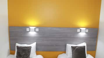 Habitació d'hotel amb dos llits, cada un amb roba de llit blanca i un capçal de llit gris. Les parets tenen un to grogós càlid.
