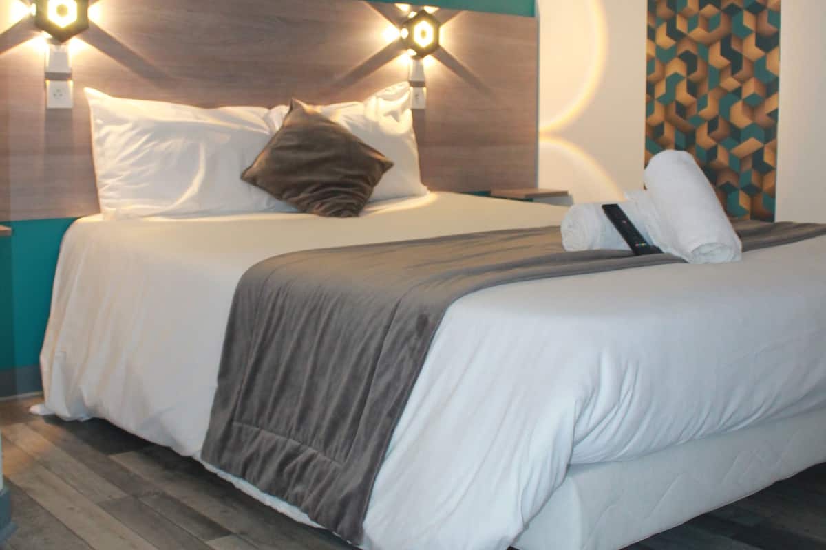 Ein modernes Hotelzimmer mit einem Bett, einem Nachttisch und einer Wandlampe.