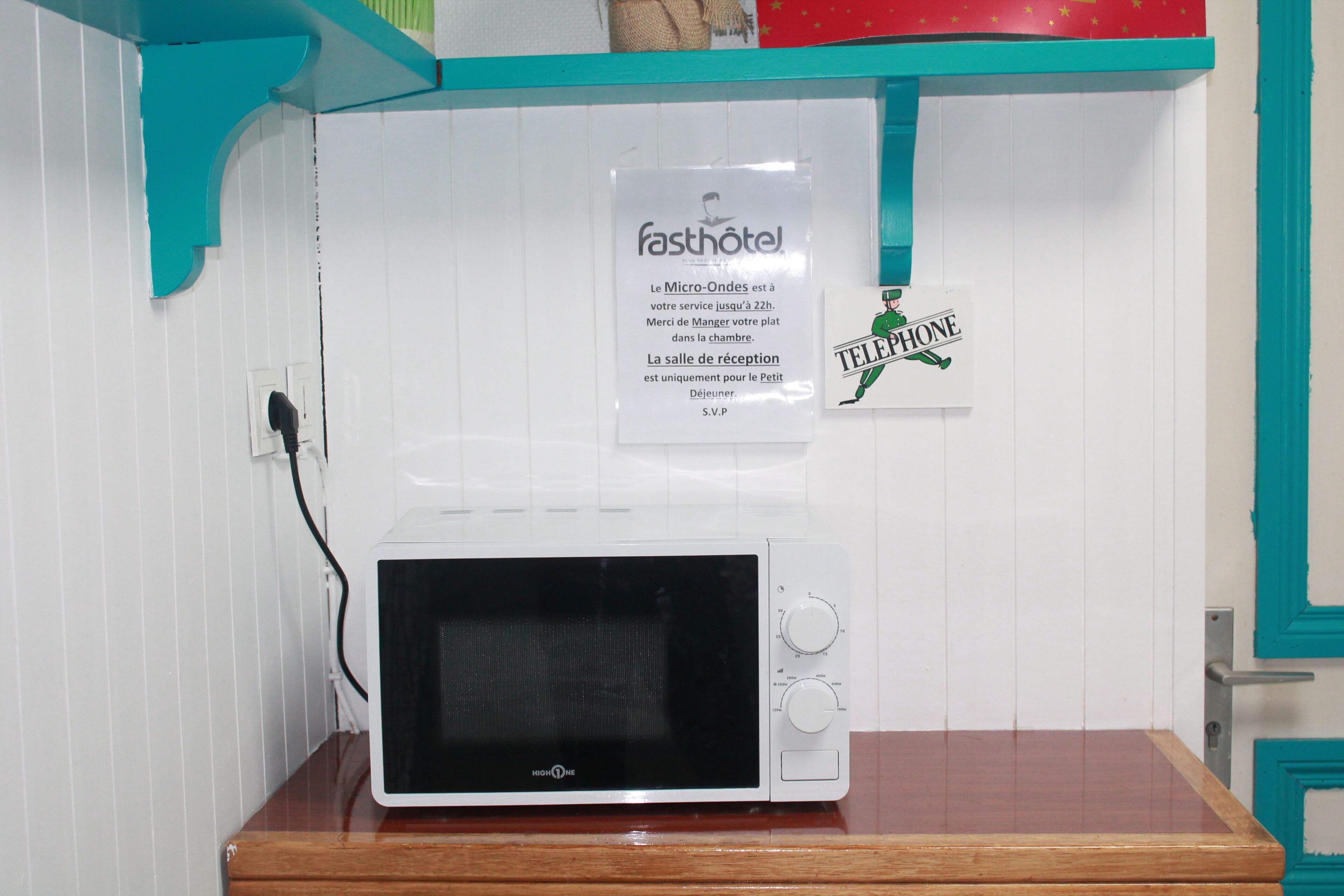Un horno microondas blanco sobre una encimera de madera, con un letrero encima.