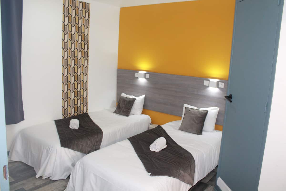 Ein Hotelzimmer mit zwei Einzelbetten, einem gemusterten Vorhang und einem modernen Wanddesign.