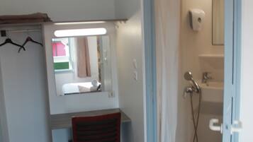 A bathroom with a shower, a sink, and a mirror.