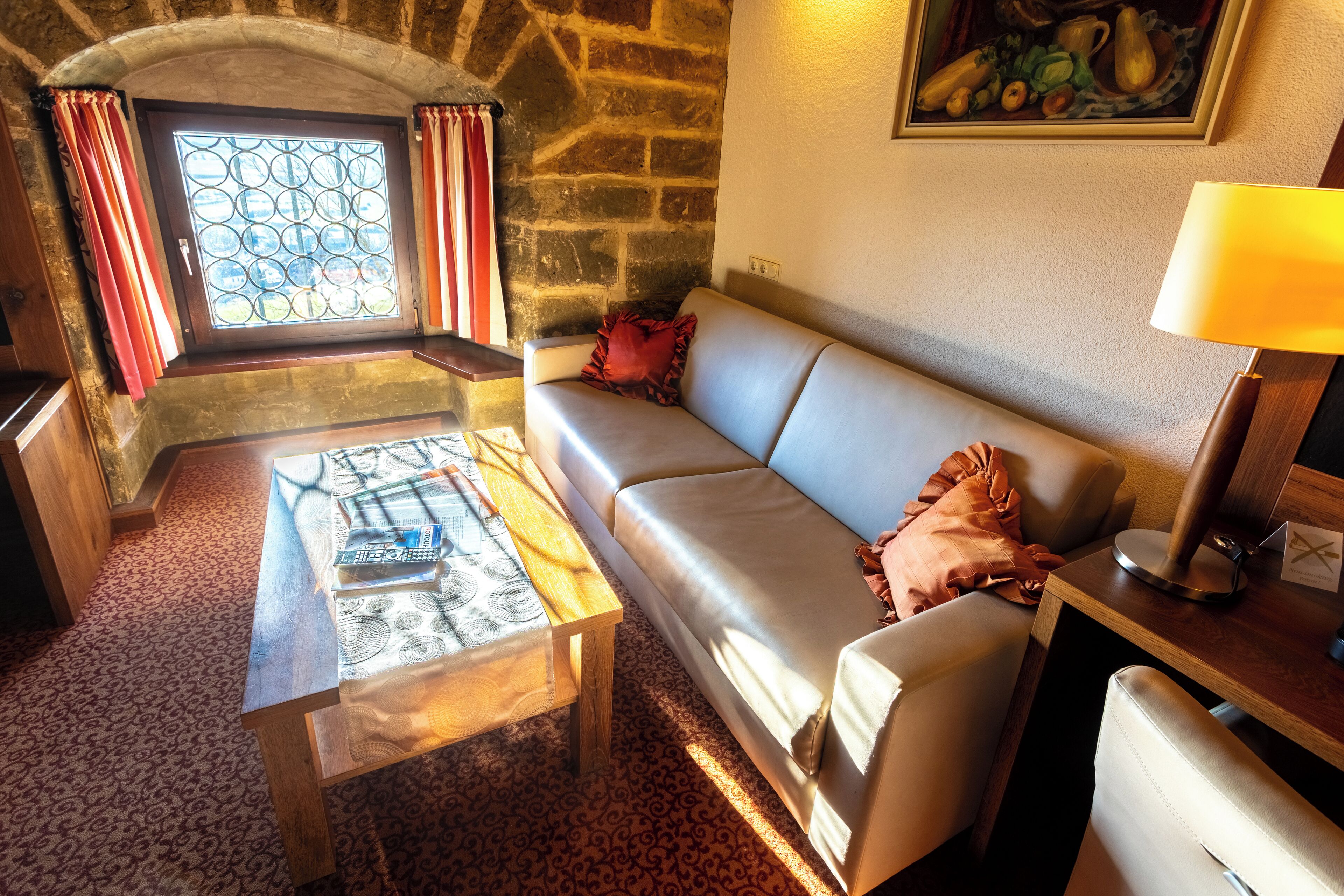 Une pièce chaleureuse avec un mur en pierre, un canapé confortable, une table basse en bois et une fenêtre avec des rideaux.