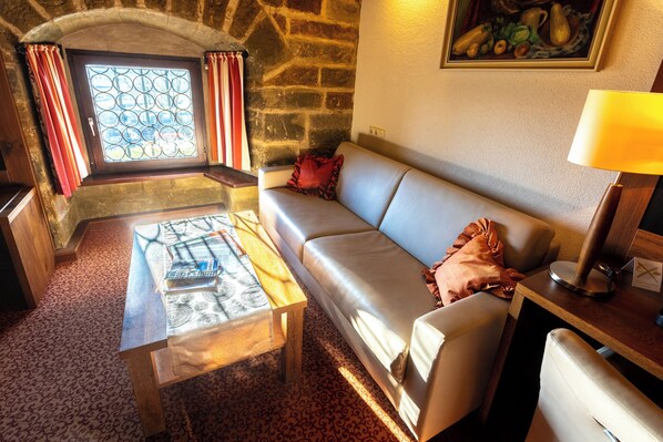A cozy room with a stone wall, a cushioned sofa, a wooden coffee table, and a window with curtains.