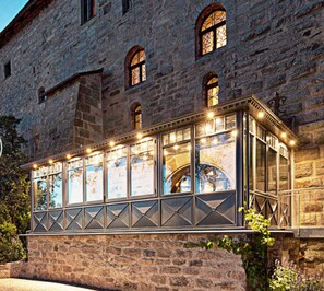 A stone building with a glass extension featuring multiple windows and a balcony.