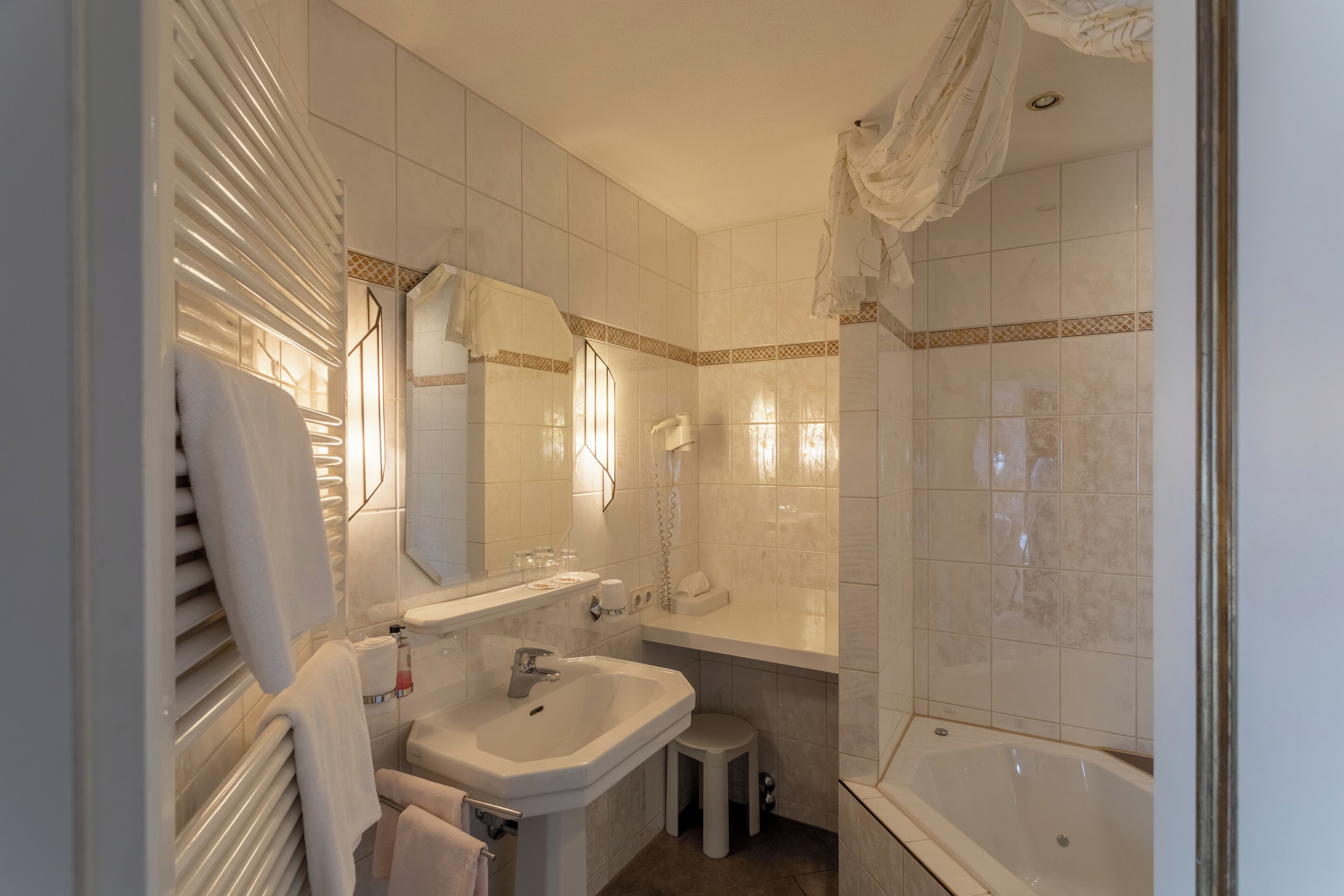 A bathroom with a sink, mirror, vanity, and bathtub.