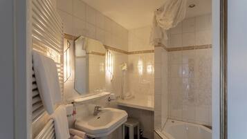 A bathroom with a sink, mirror, vanity, and bathtub.