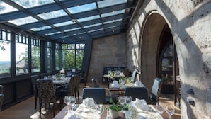Un restaurante con mesas dispuestas para comer, ventanas amplias y paredes de piedra.