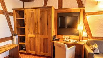 A cozy room with wooden furniture, a flat-screen TV, a desk with a lamp, and a comfortable seating area.