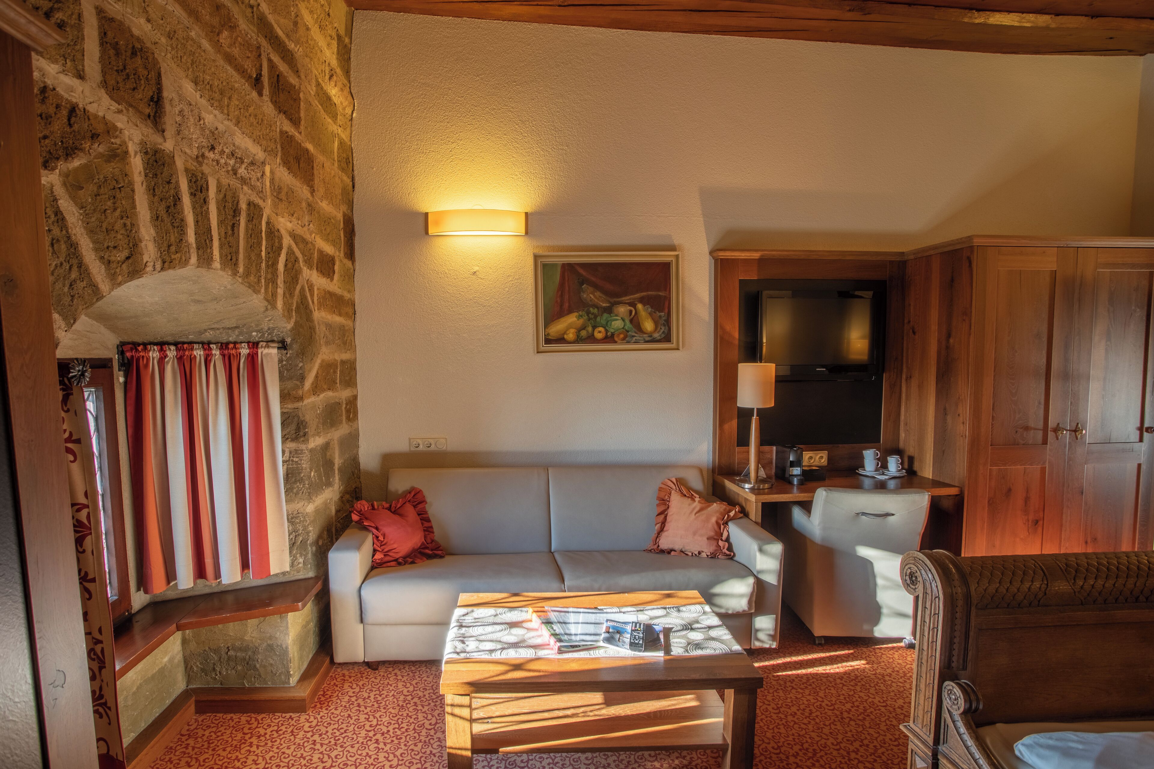 A cozy living room with a stone wall, a white sofa, a wooden coffee table, and a television.