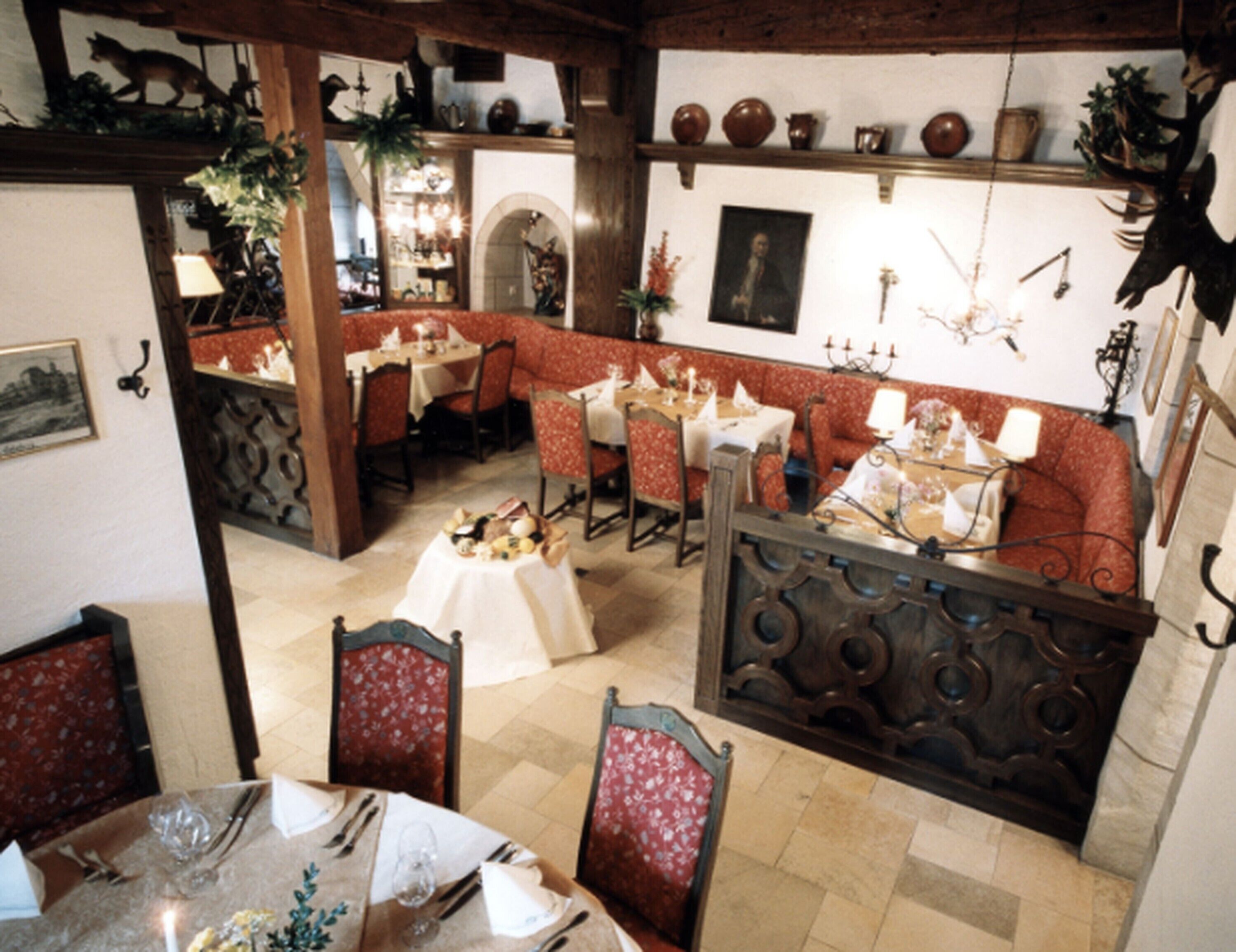 A dining area with a high ceiling, red upholstered seating, and a variety of table settings.
