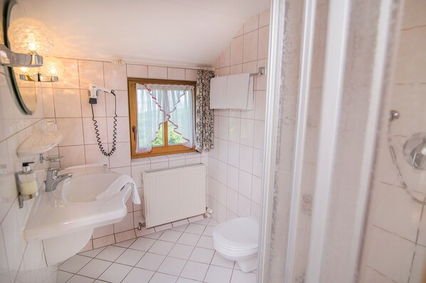 A bathroom with a sink, toilet, and a window with curtains.