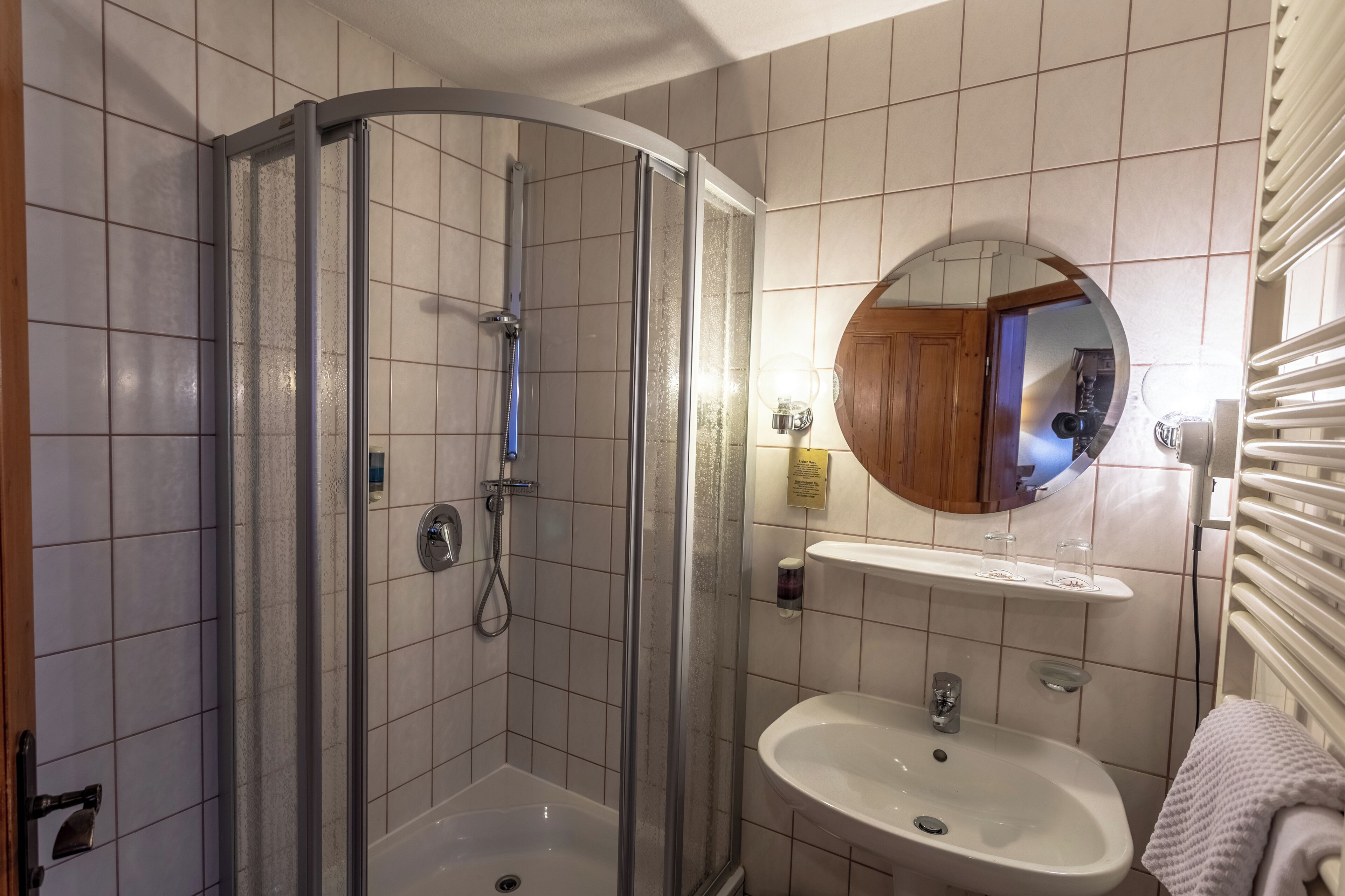 A bathroom with a glass-enclosed shower, a sink with a mirror, and a towel rack.