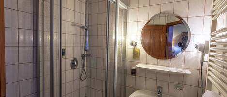 A bathroom with a glass-enclosed shower, a sink with a mirror, and a towel rack.