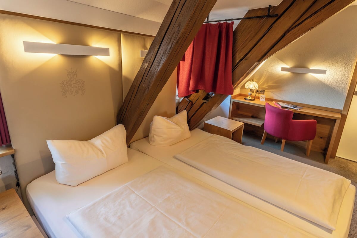 A bedroom with a bed, a desk, a chair, and a red curtain.