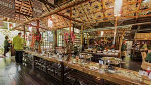 A traditional wooden restaurant with a high ceiling and patterned ceiling tiles.