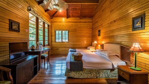 A wooden cabin room with a bed, desk, and chair.