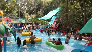 A water park with inflatable rafts, slides, and a pool area surrounded by trees.
