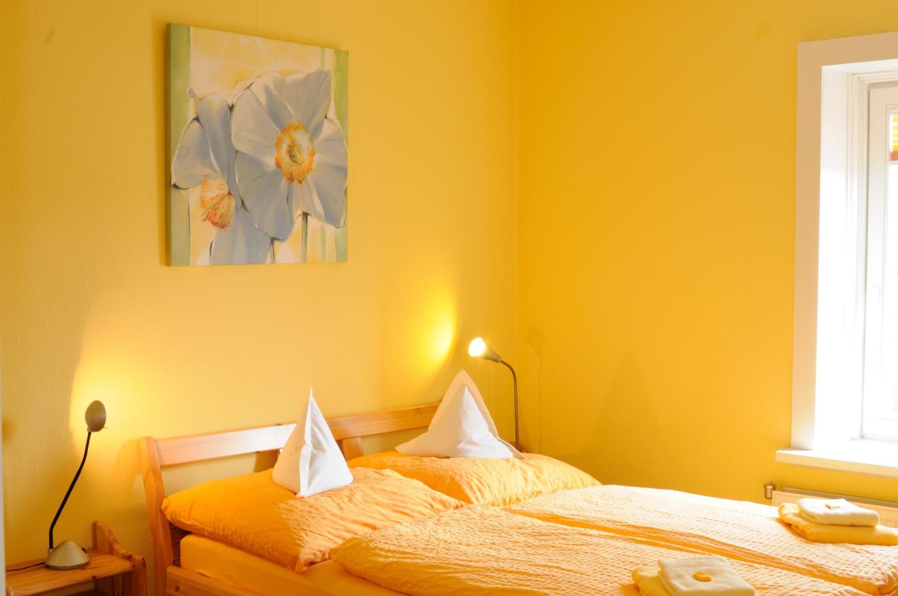 A room with a bed, a bedside table, a lamp, and a painting on the wall.