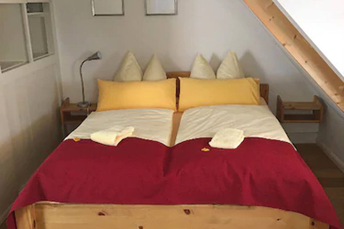 A room with a wooden bed, two bedside tables, a lamp, and two framed pictures on the wall.