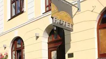 A hotel with a yellow facade, a signboard with the word "HOTEL" and a golden emblem, and a bicycle parked outside.