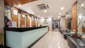 A hotel reception area with a modern design, featuring a reception desk, clocks, and a sign for A25 HOTEL. - A25 Hotel - 45 Phan Chu Trinh (Hanoi)