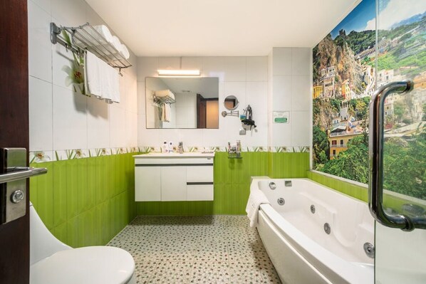 A bathroom with a green and white tiled wall, a large mirror, a sink, a toilet, and a bathtub. - A25 Hotel - 45 Phan Chu Trinh (Hanoi)