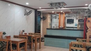 A restaurant with wooden tables and chairs, a kitchen area with appliances, and hanging crystal light fixtures. - A25 Hotel - 45 Phan Chu Trinh (Hanoi)
