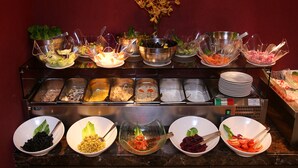 A buffet with various food items and utensils. - AlHamra Hotel (Sharjah)
