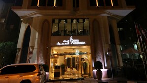 Un bâtiment d’hôtel avec des fenêtres illuminées et une enseigne indiquant « Hôtel Al Hamra ».
