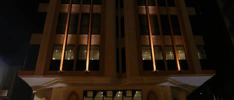 A hotel building with illuminated windows and a sign reading "Hotel Al Hamra".