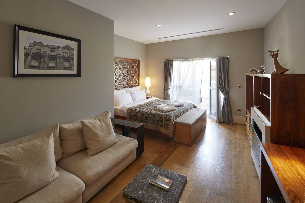 A hotel room with a bed, a sofa, a coffee table, and a wooden cabinet.