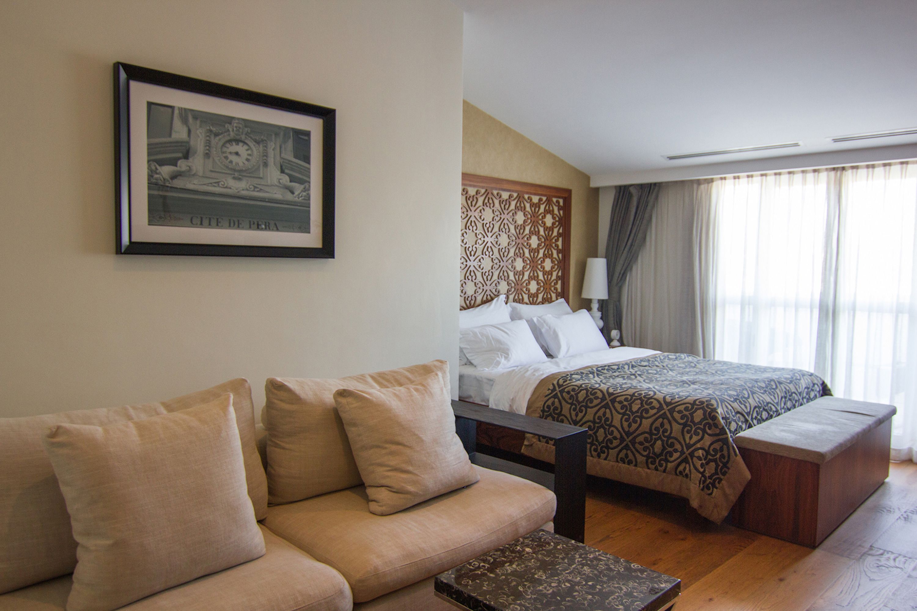 A hotel room with a bed, a sofa, a nightstand, and a framed picture on the wall.