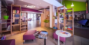A modern library with wooden bookshelves, purple seating, and a green accent wall.
