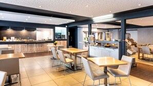 A modern restaurant with a bar area, seating, and a kitchen in the background. - ibis Styles Brive La Gaillarde (Brive-la-Gaillarde)