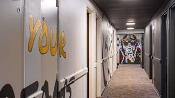 A hallway with a carpeted floor, doors with 'YOUR TEAM' painted on them, and a colorful mural on the wall.