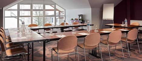 A conference room with a long table, chairs, a projector screen, and large windows.