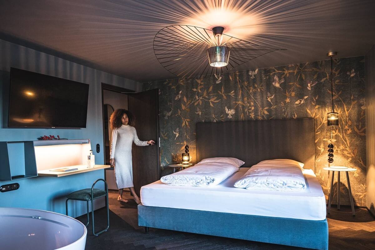 A modern bedroom with a large bed, bedside tables, a desk, and a large mirror.